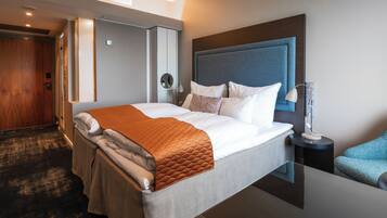 Une chambre d’hôtel moderne avec un grand lit, une table de chevet avec une lampe et une armoire.