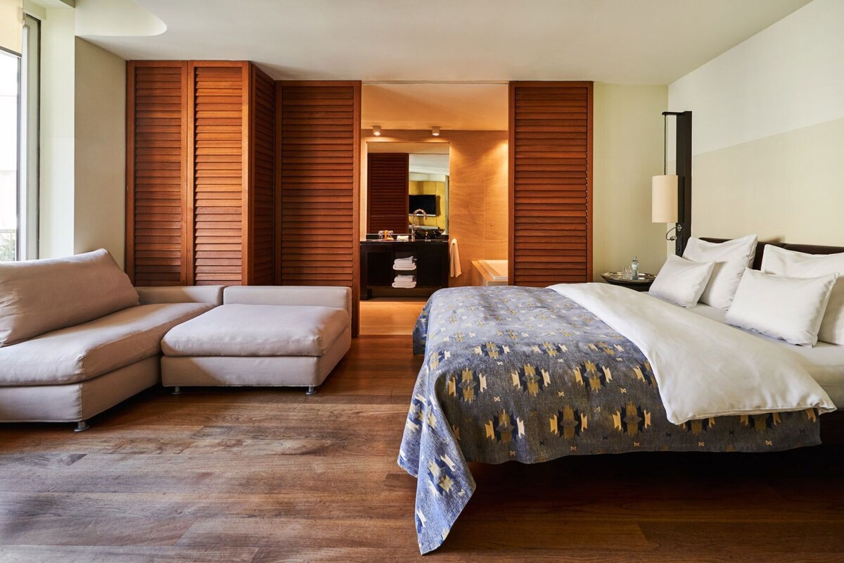 Een moderne hotelkamer met een bed, een bank, een bureau en een spiegel.