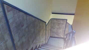 A staircase with stone walls and a metal handrail.