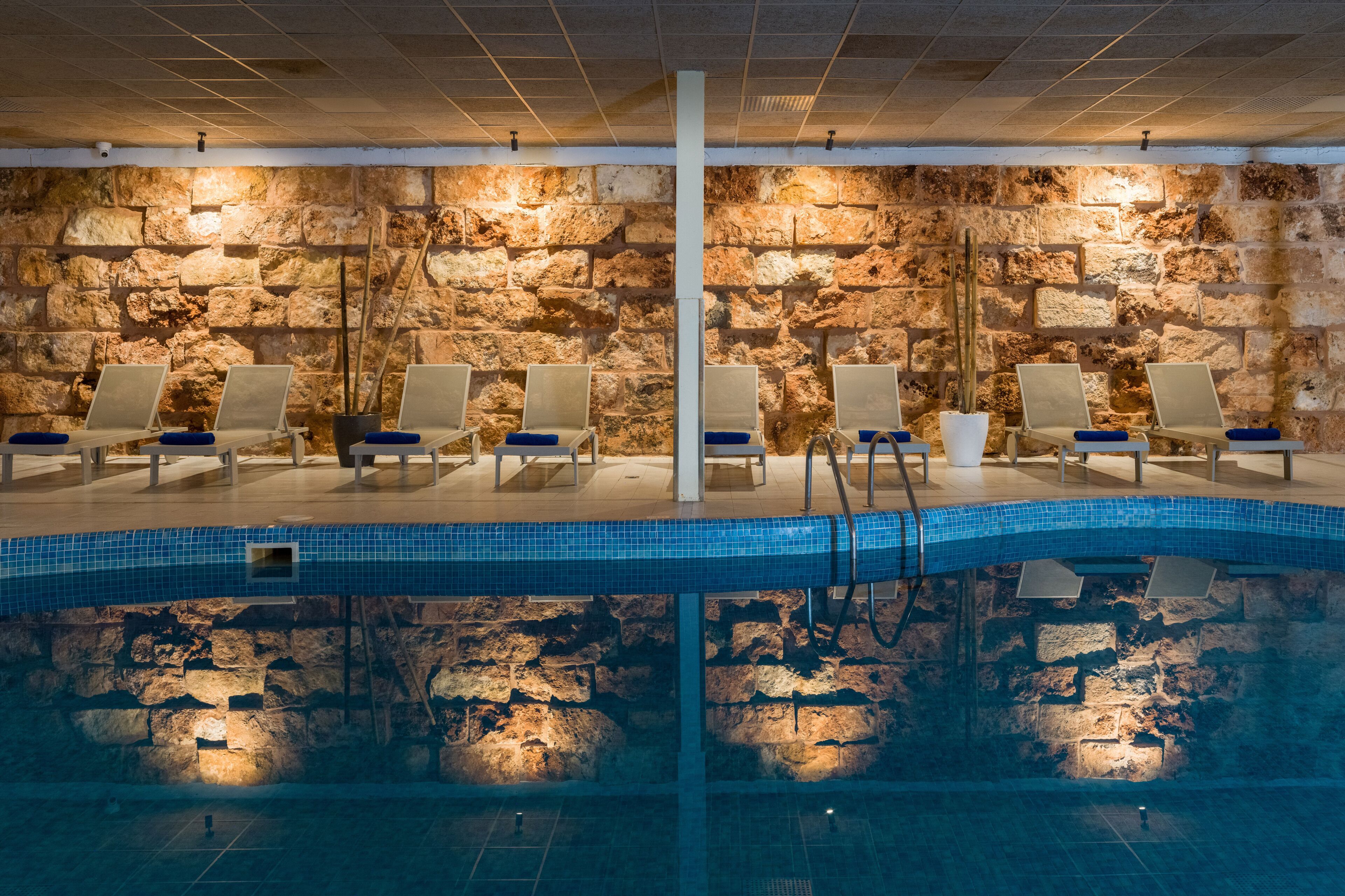 A swimming pool with lounge chairs and stone walls.