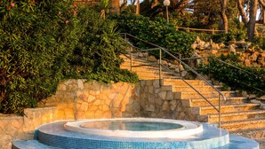 Un jacuzzi con pared de piedra y escaleras que lo conducen.