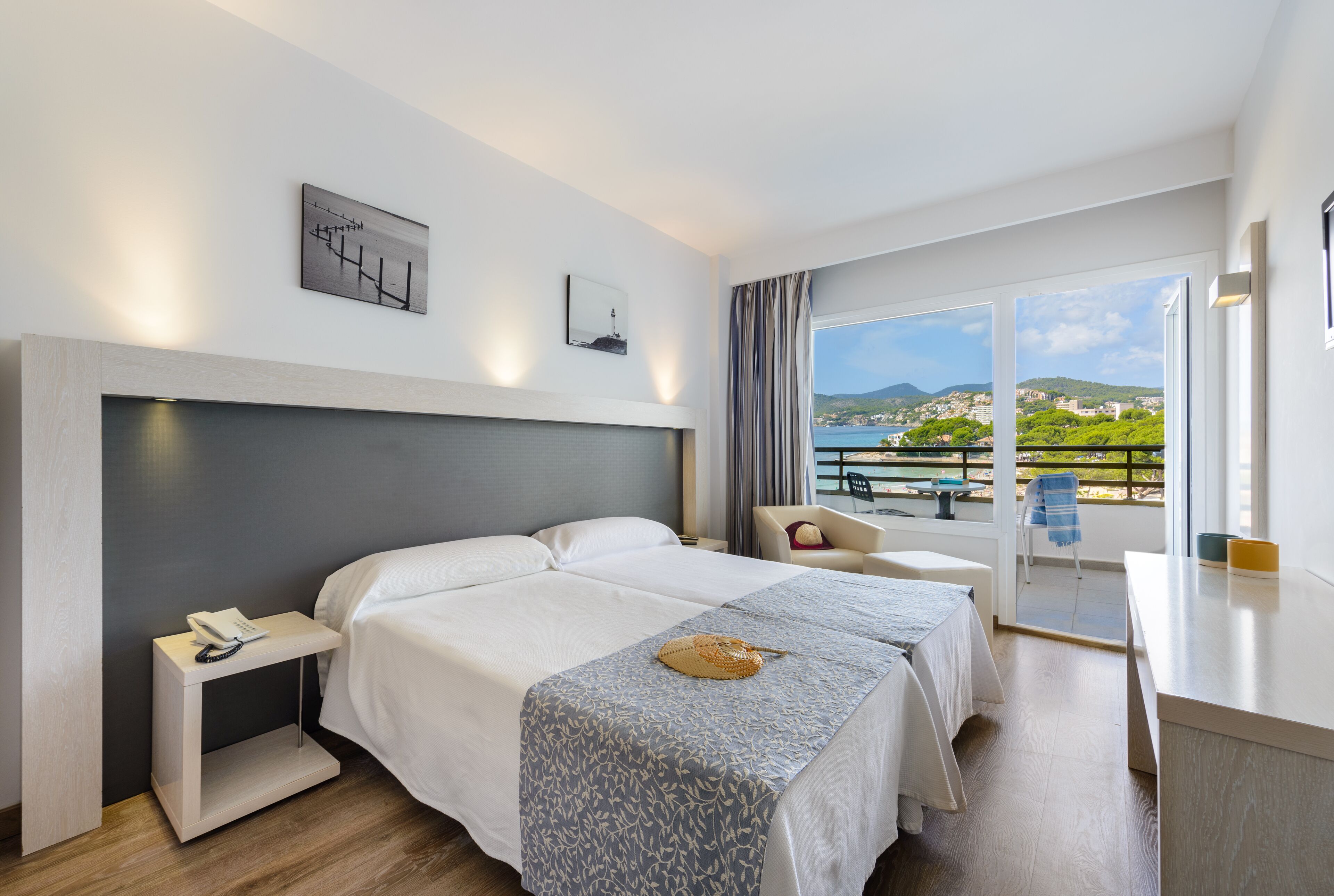 A hotel room with a bed, bedside table, and a view of the sea.