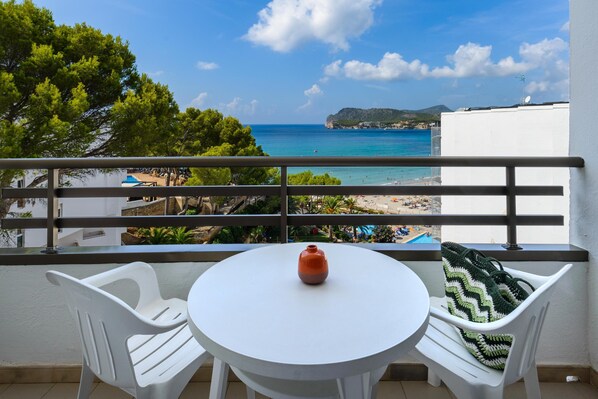 A balcony with a white table, two white chairs, and a view of a beach and sea. - Hotel Vibra Beverly Playa (Calvia)