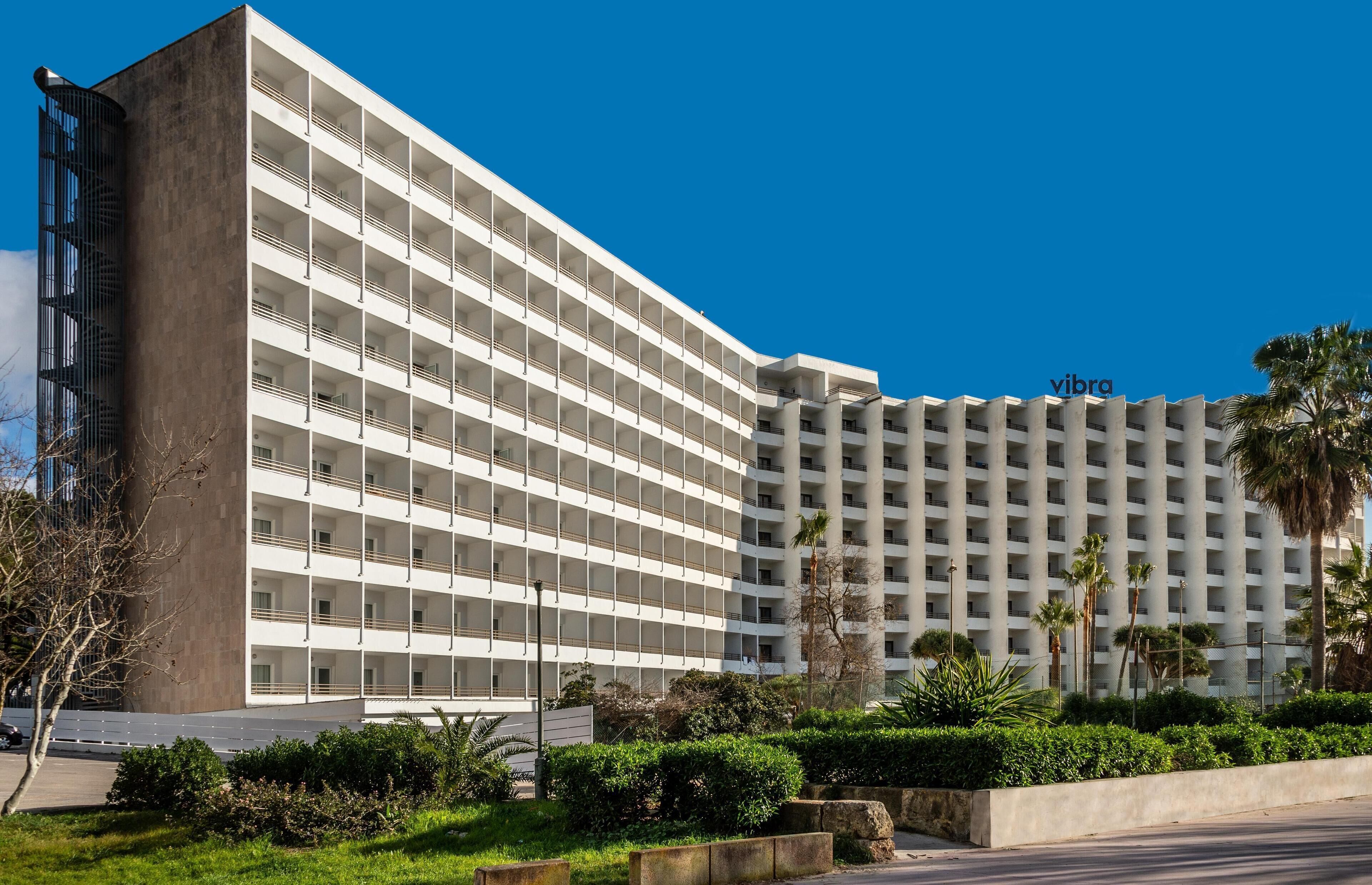 A multi-story hotel with a modern design, featuring a prominent 'vibra' sign on the top right.