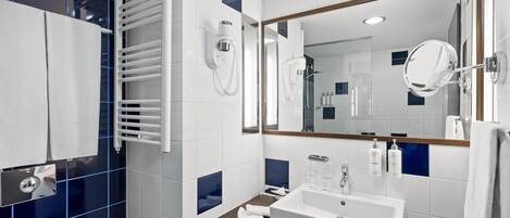 A modern bathroom with a large mirror, a white sink, and a towel rack.