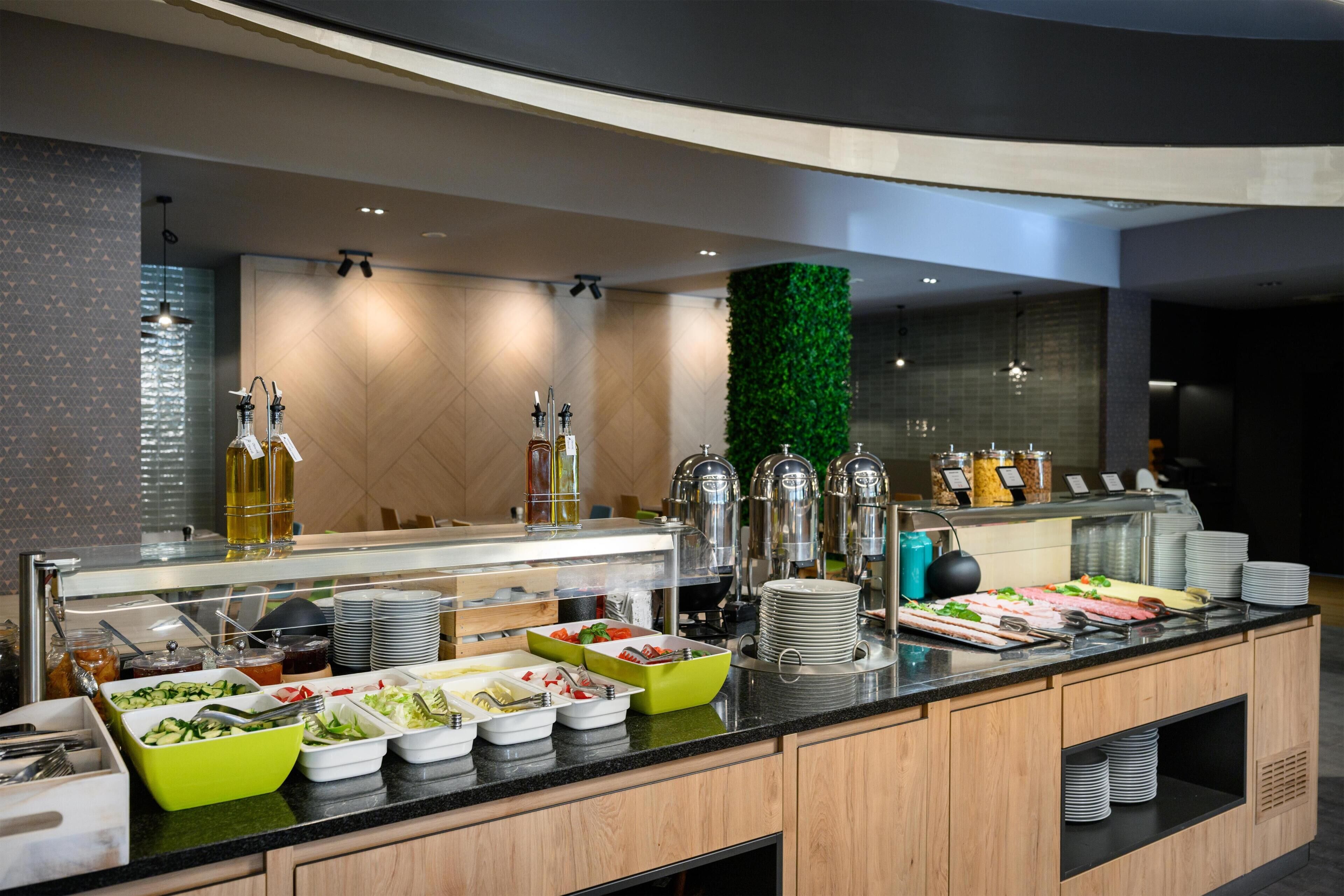 A buffet with various food items, a green wall, and a modern design.