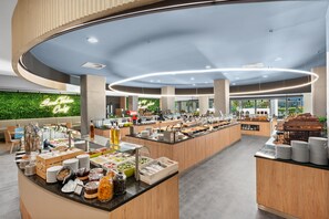 A modern breakfast buffet with a variety of food options, a green wall with a neon sign, and a spacious layout.