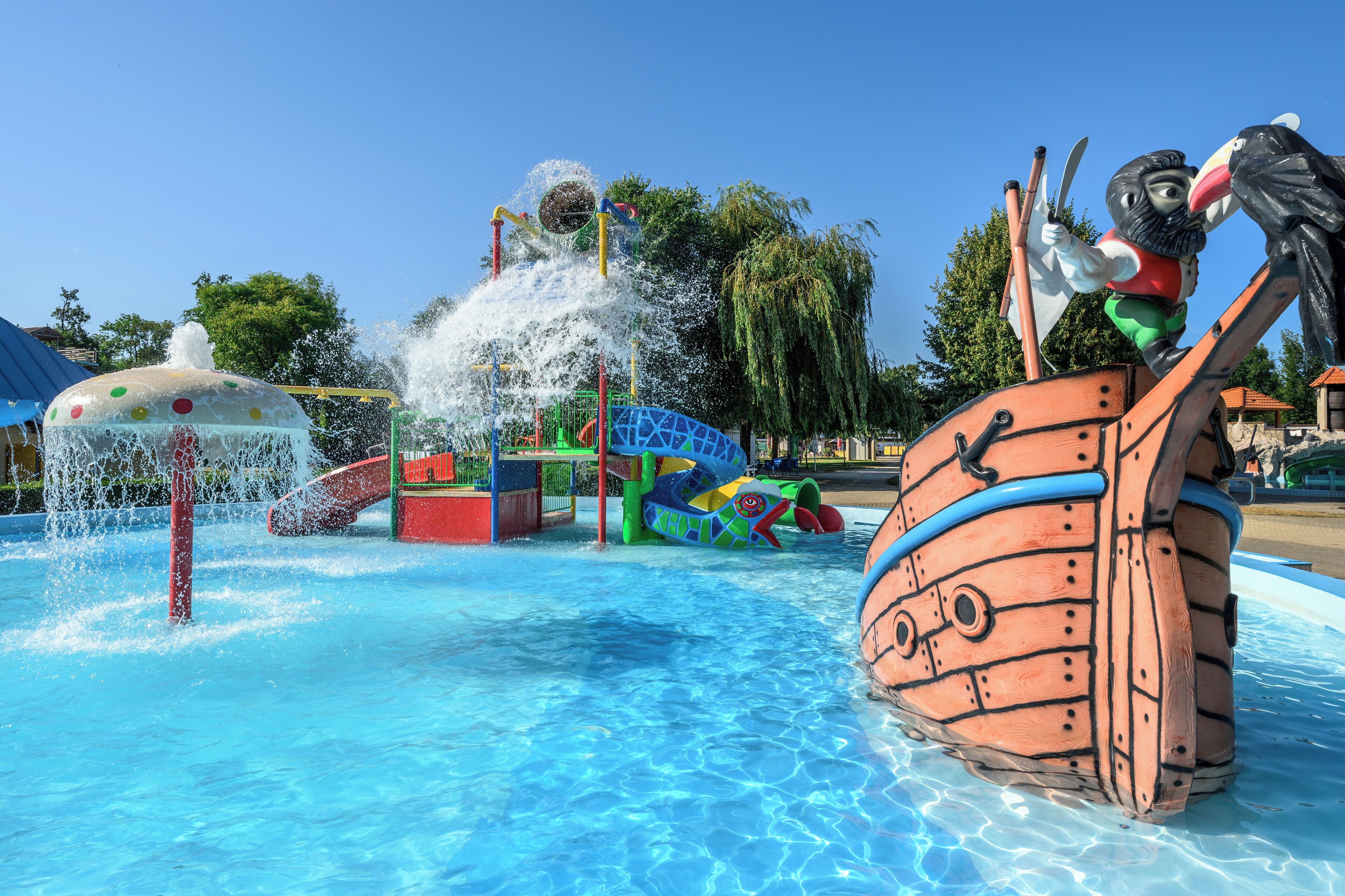 Un parc aquatique doté d’une structure de jeux en forme de bateau et d’une fontaine.