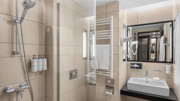 A modern bathroom with a glass-enclosed shower, a white sink, and a towel rack.