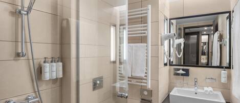 Een moderne badkamer met een douchecabine van glas, een witte wastafel en een handdoekrek.