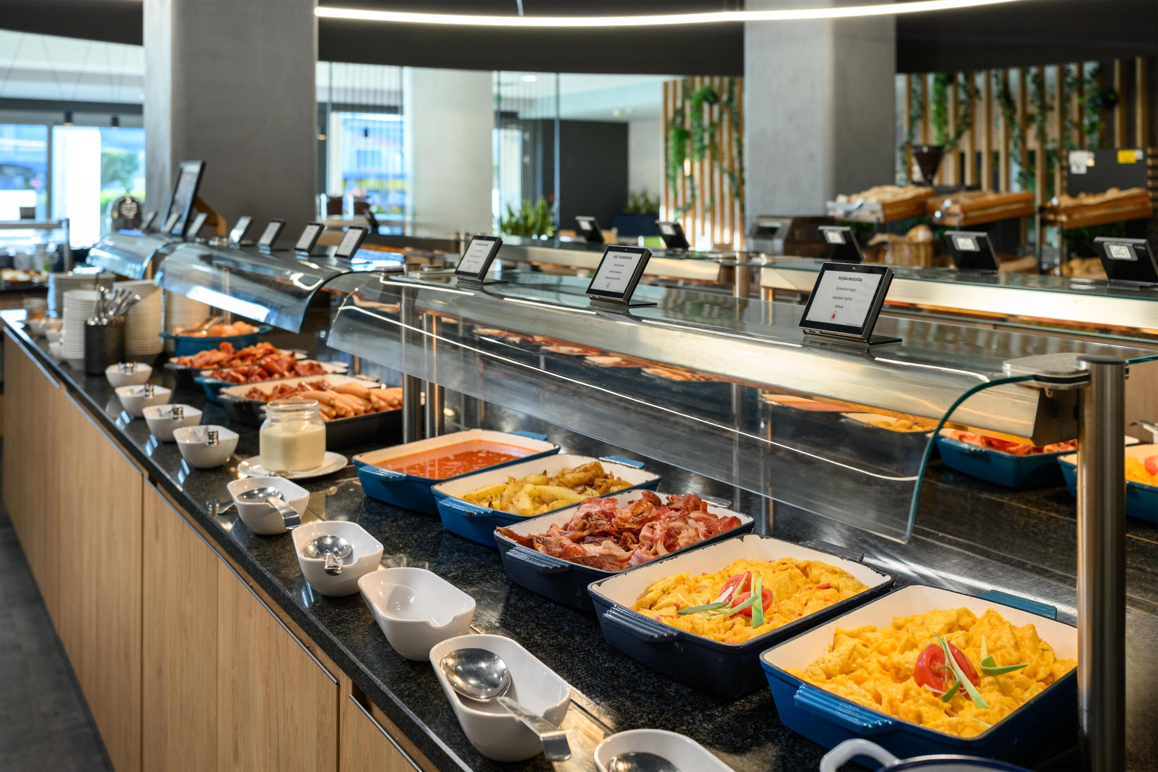 Buffet com diversas opções de comida, incluindo carnes, saladas e produtos de panificação.