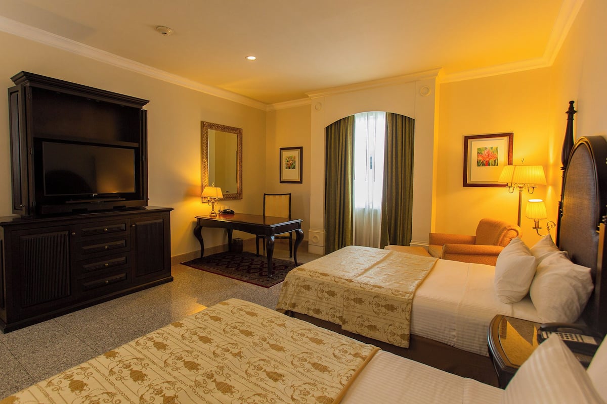 Een hotelkamer met twee bedden, een televisie, een bureau en een stoel.