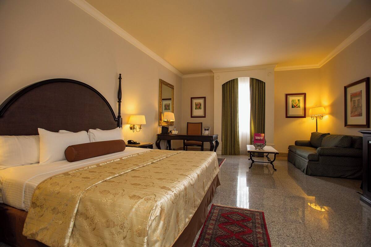 Een hotelkamer met een groot bed, een bureau, een stoel, een bank en een kleine tafel.