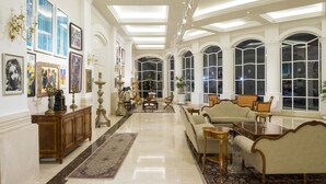 Un'ampia hall, arredata con eleganza, caratterizzata da soffitti alti, ampie finestre e diverse tipologie di posti a sedere.