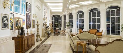 A spacious, elegantly furnished lobby with high ceilings, large windows, and a variety of seating arrangements.