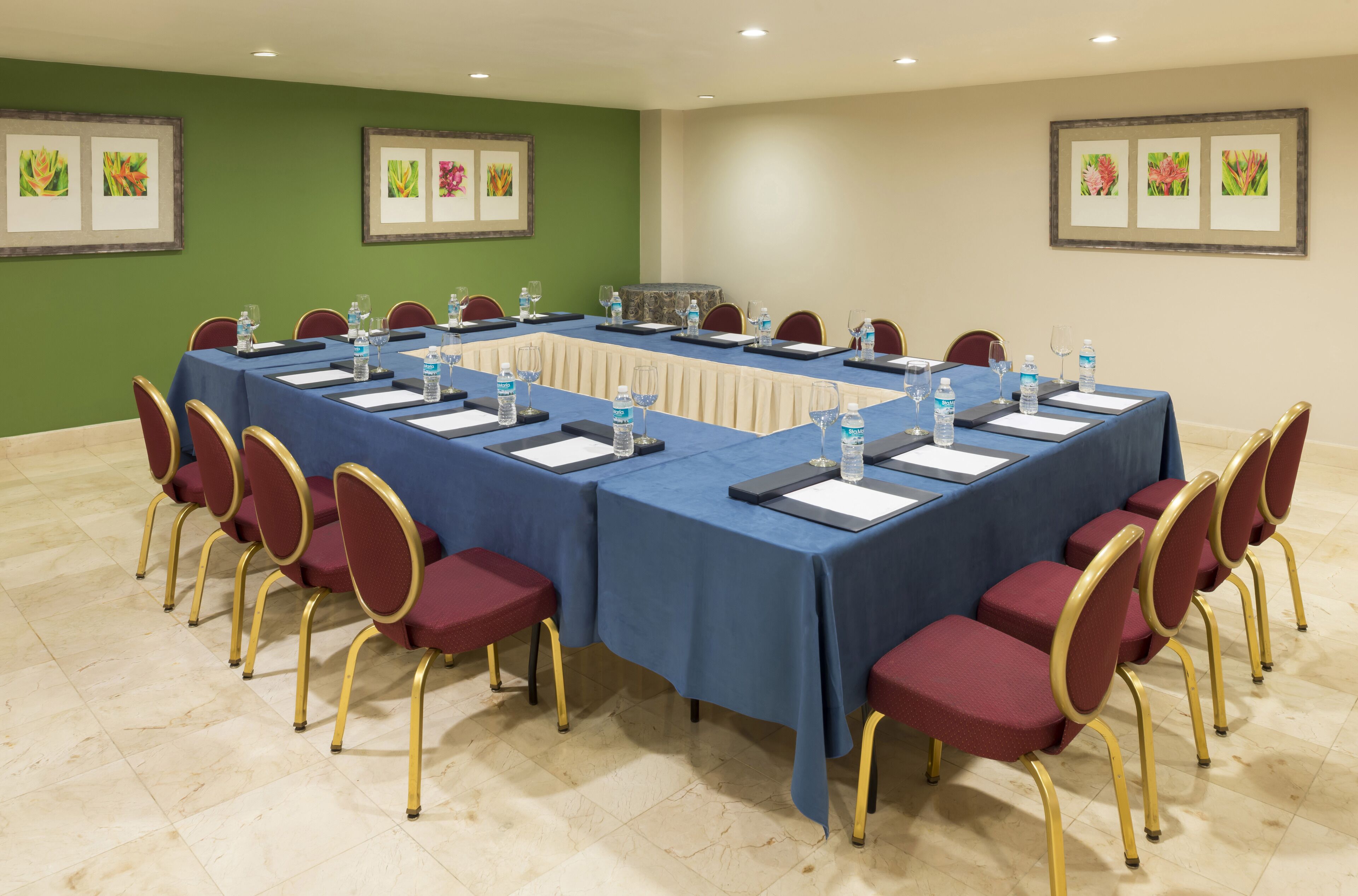 Un salón de conferencias con una larga mesa, sillas, botellas de agua y tarjetas de identificación.