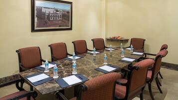 A conference room with a marble table, six chairs, water bottles, and a framed picture on the wall.