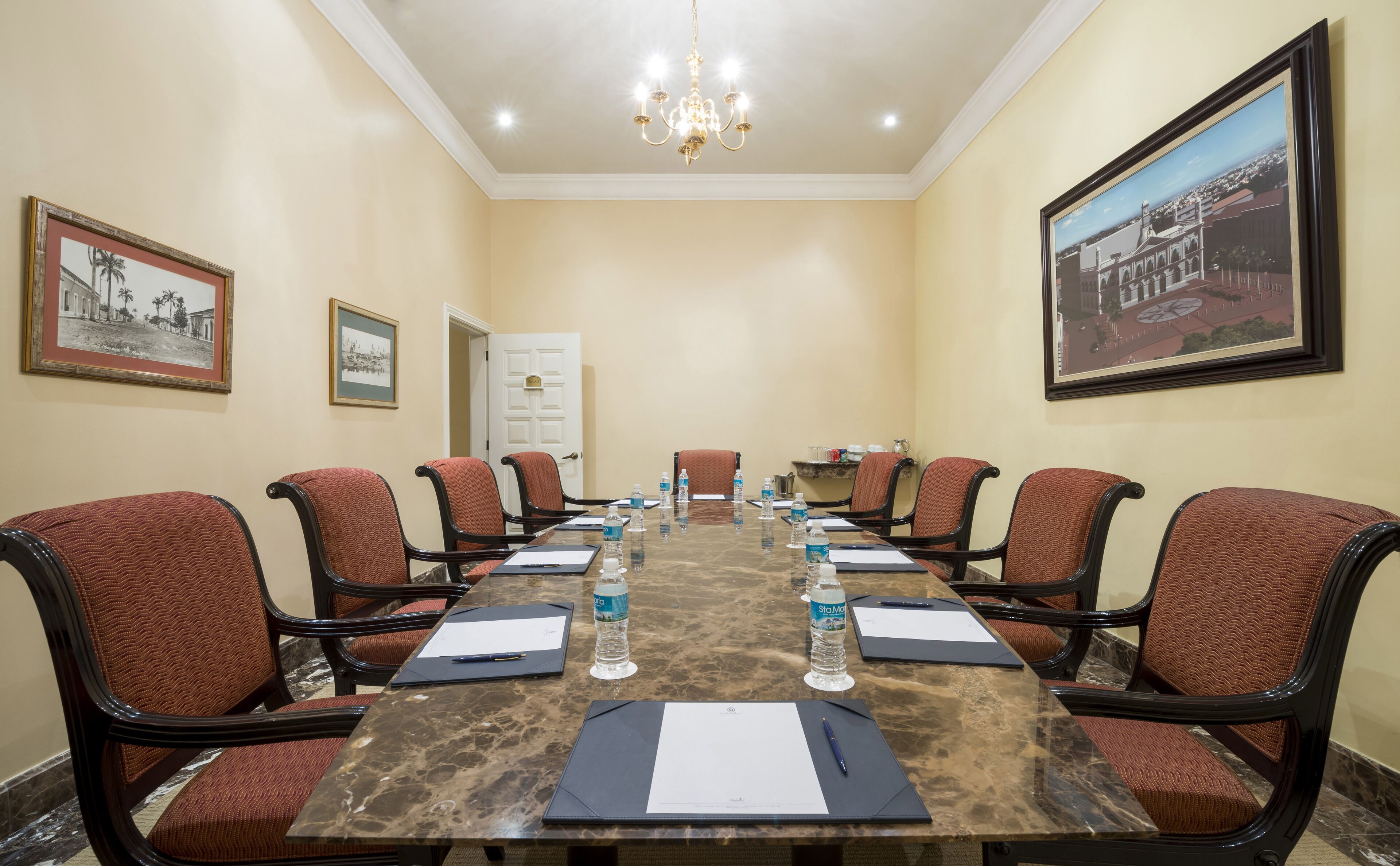 A conference room with a long table, chairs, water bottles, and documents.