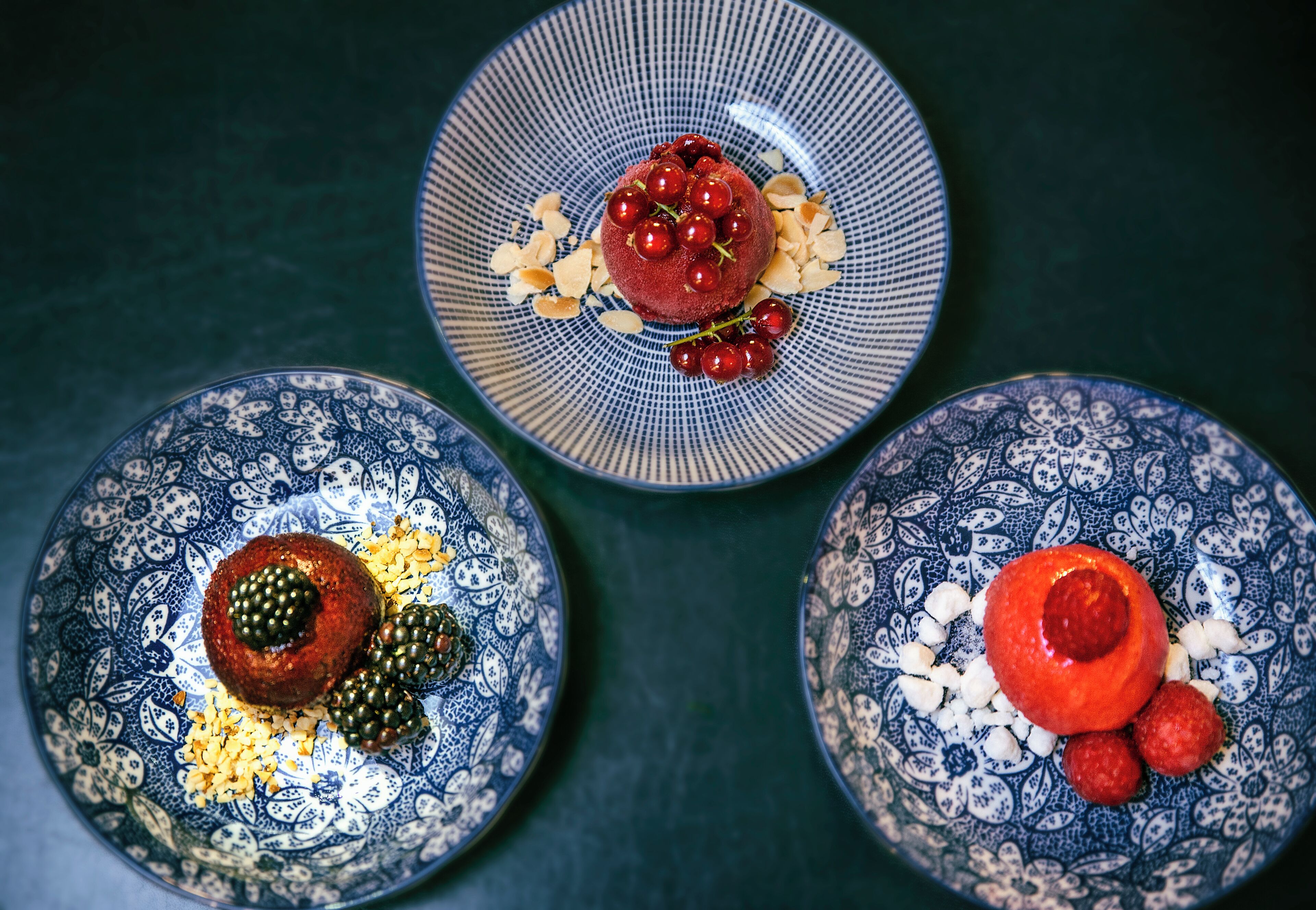 Three plates with food, each with a different pattern and garnishes.