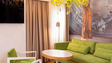 A modern living room with a green sofa, white armchairs, a round coffee table, and a yellow chandelier.