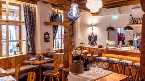 Een rustiek interieur met houten balken, een bar en zitgedeeltes.