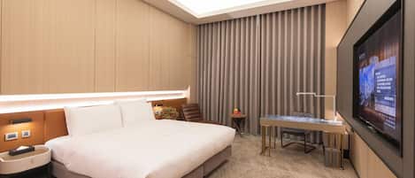 Una habitación de hotel moderna con una cama grande, un escritorio, un televisor de pantalla plana y una lámpara en el techo.