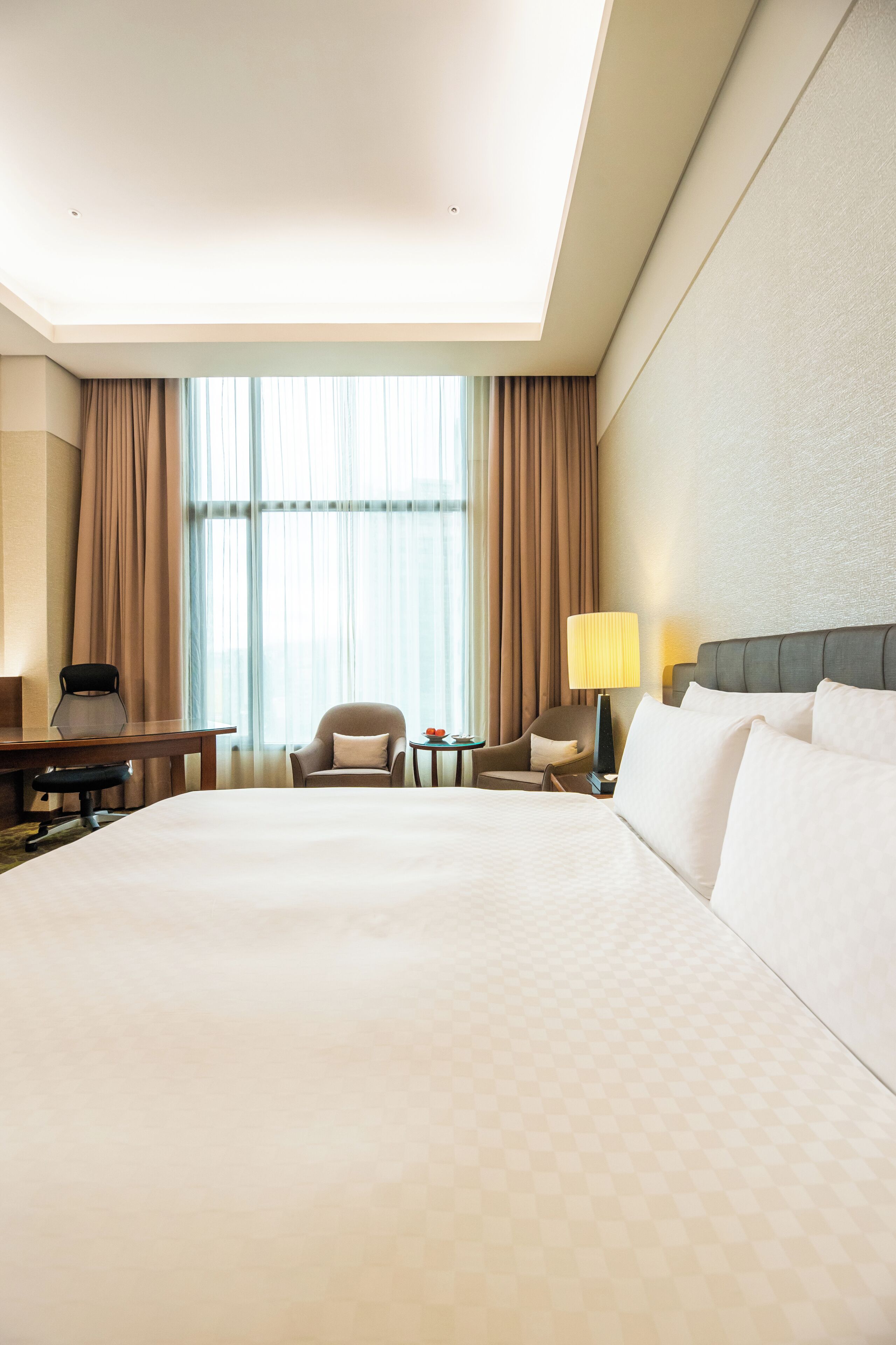 Una habitación de hotel con una cama grande, dos sillones, un escritorio y una lámpara.