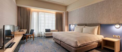 A hotel room with a large bed, a desk with a chair, a TV, and a small table.