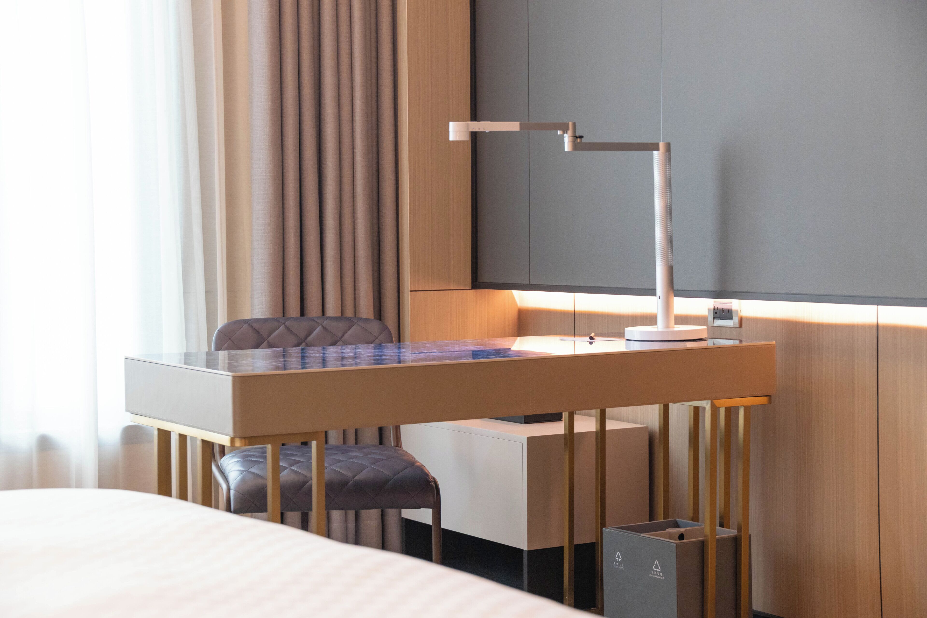 Et hotelværelse med en seng, et skrivebord med lampe, en stol og et klædeskab.