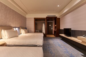 Een hotelkamer met twee bedden, een televisie, een bureau en een inloopkast.