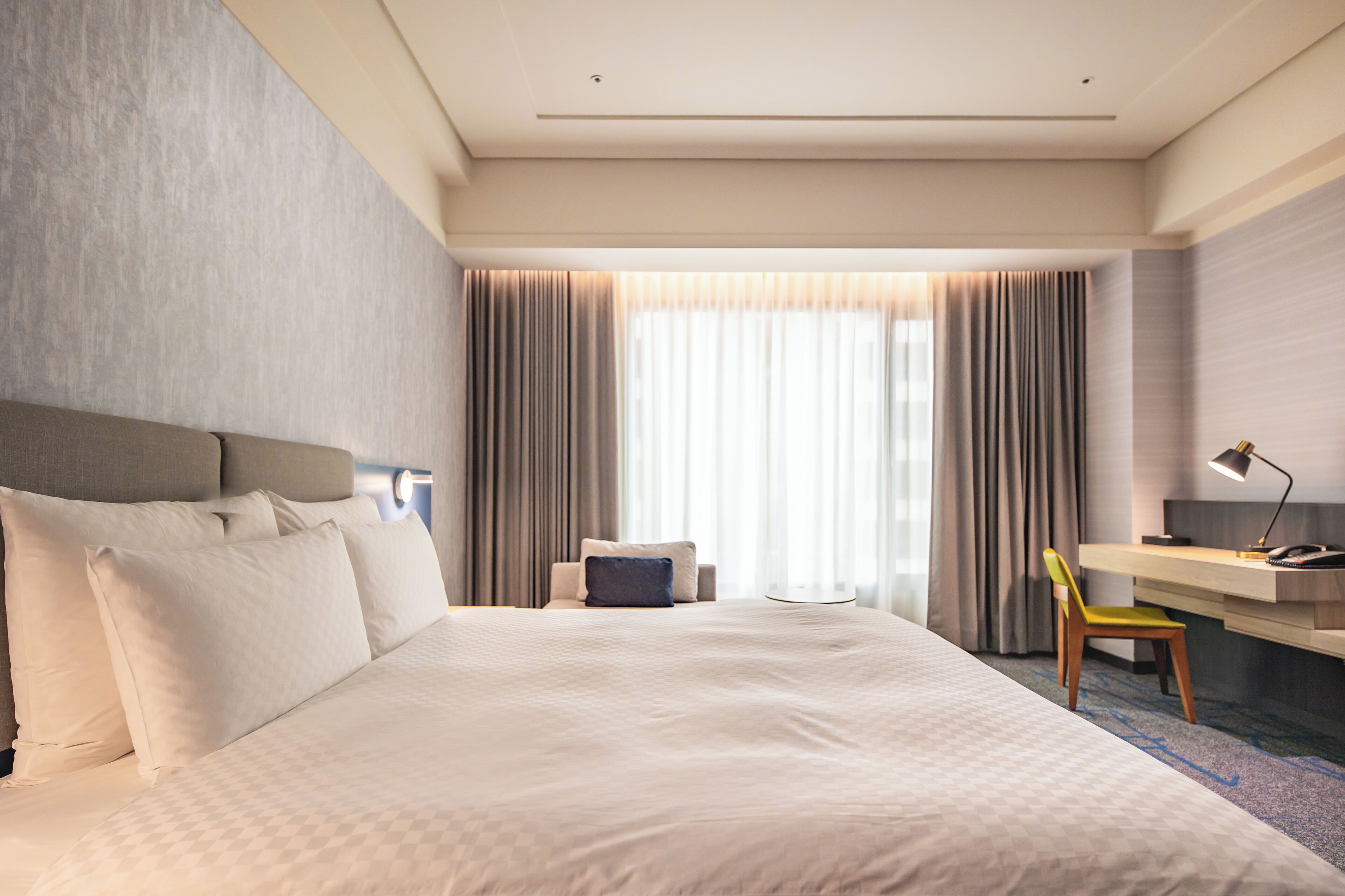 A hotel room with a large bed, a desk, and a chair.