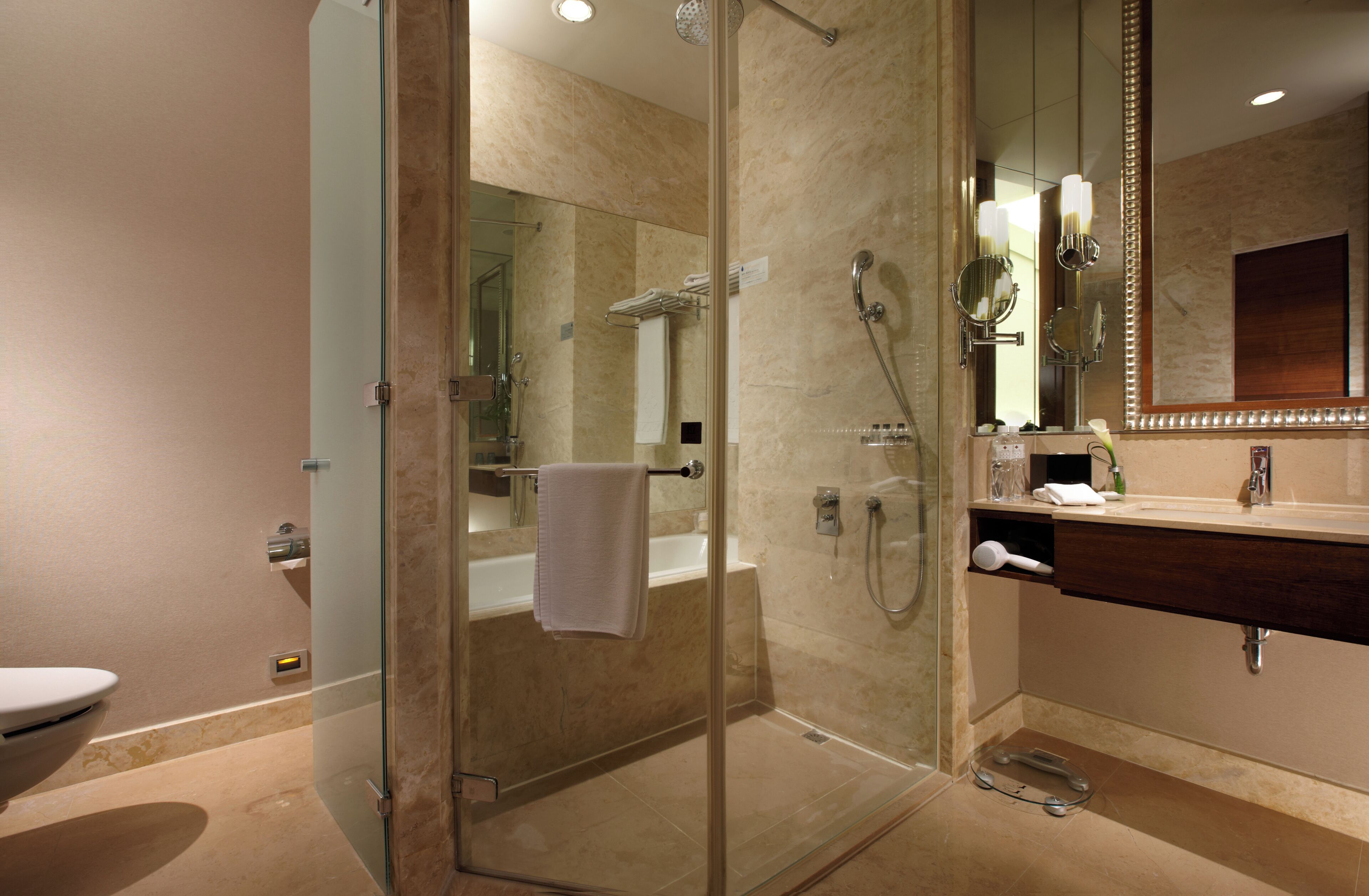 Un baño moderno con ducha de vidrio, tocador con espejo y retrete.