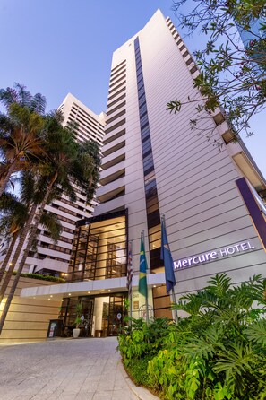 Um edifício moderno de hotel com entrada destacada, grandes janelas e uma bandeira.