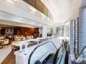 A modern hotel lobby with a central seating area, a glass railing, and an escalator. - Mercure São Paulo Grand Plaza Paulista (São Paulo)