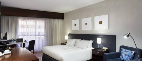Una habitación de hotel con cama, escritorio, silla y sofá.