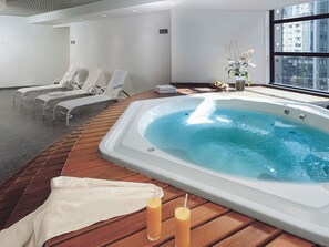 A modern indoor pool area with a hot tub, lounge chairs, and a wooden deck. - Mercure São Paulo Grand Plaza Paulista (São Paulo)