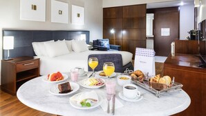A hotel room with a bed, bedside table, and a breakfast table with various food items and drinks. - Mercure São Paulo Grand Plaza Paulista (São Paulo)