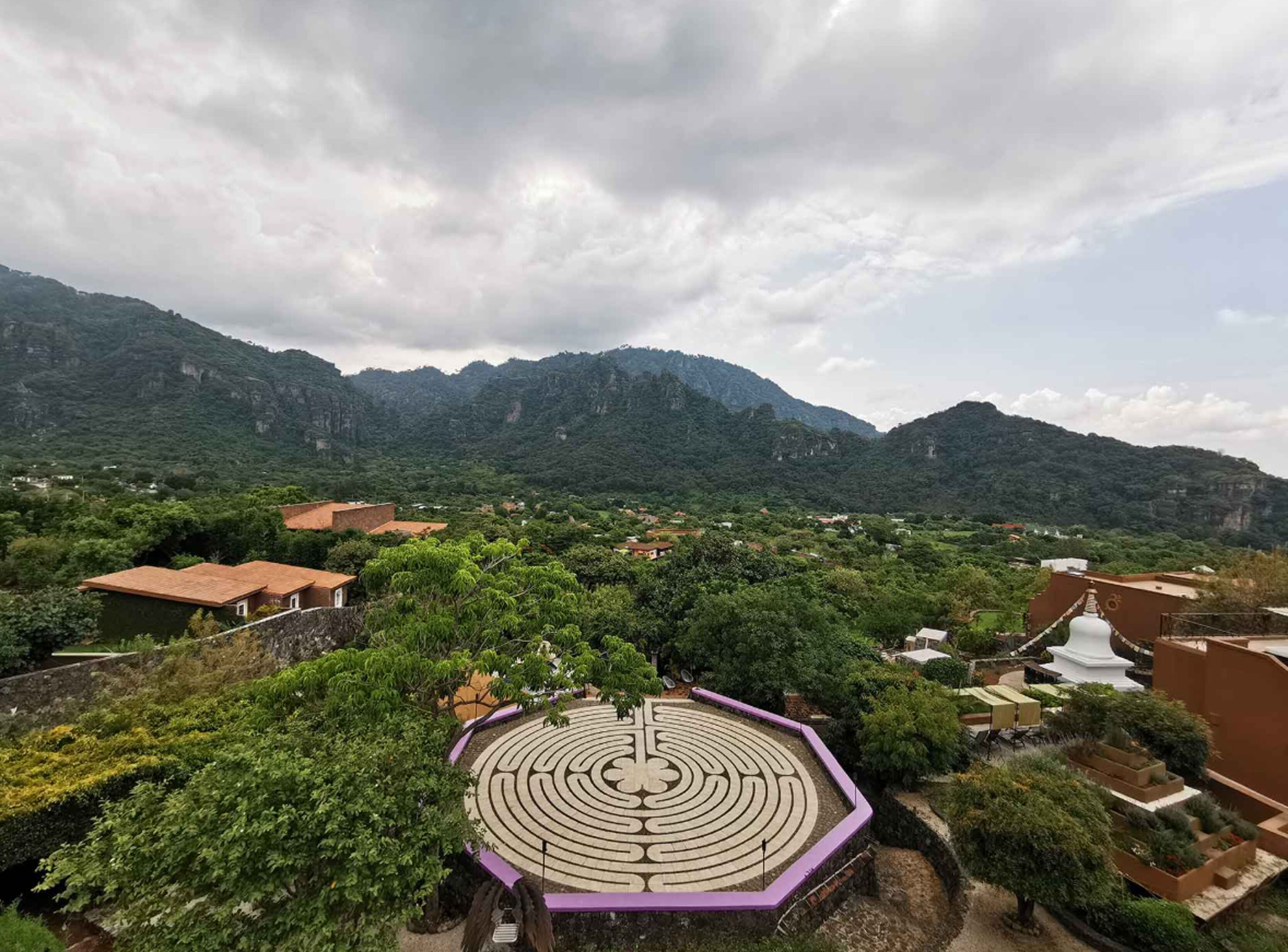 A mountainous landscape with a labyrinth garden and traditional buildings.