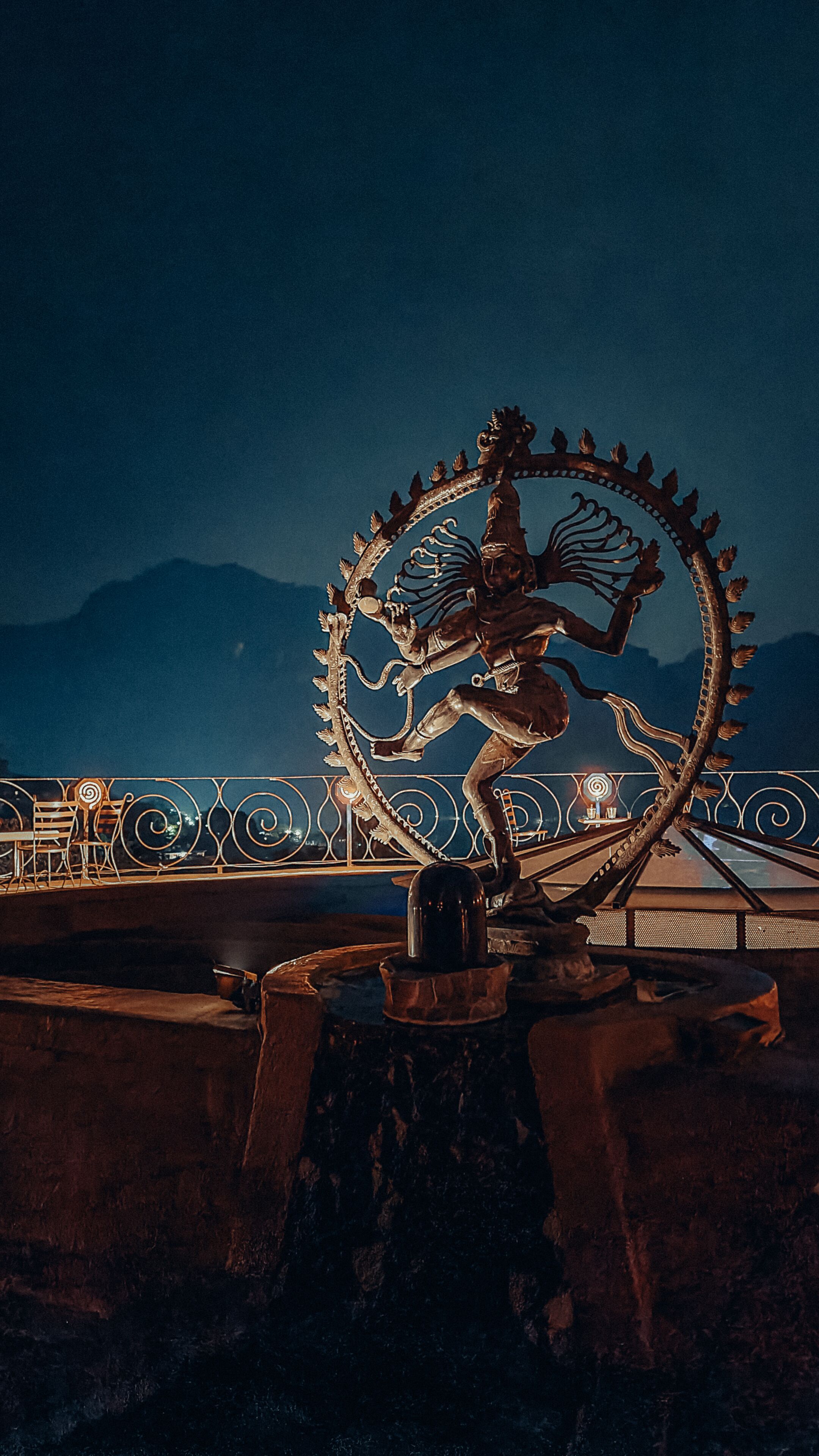 A metal sculpture of a figure riding a mythical creature, set against a night sky with mountains in the background.