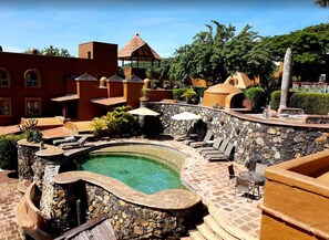 A pool area with stone walls, lounge chairs, and a hot tub. - Hostal de la Luz (Amatlán)