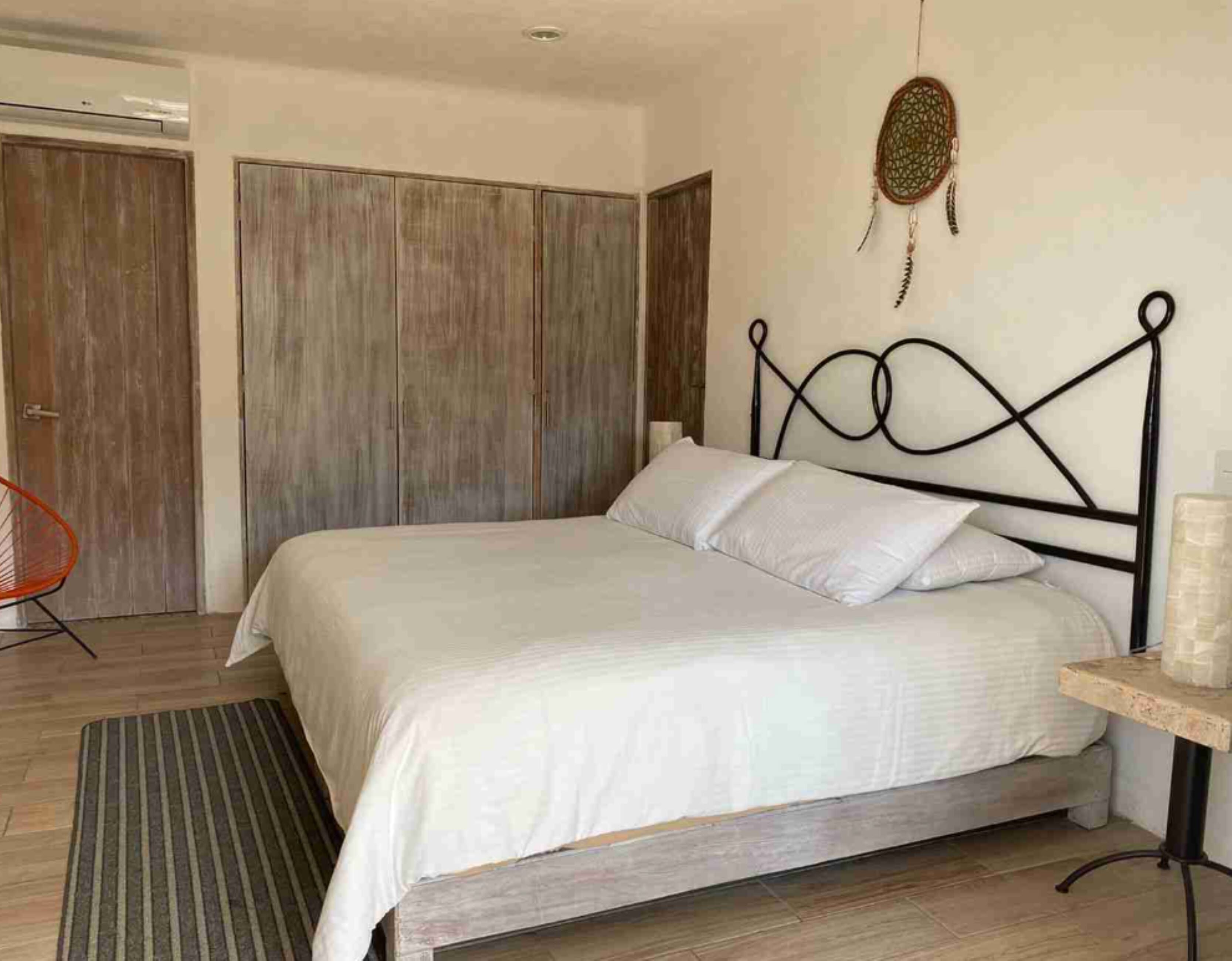 A bedroom with a bed, a chair, a bedside table, and a wardrobe.