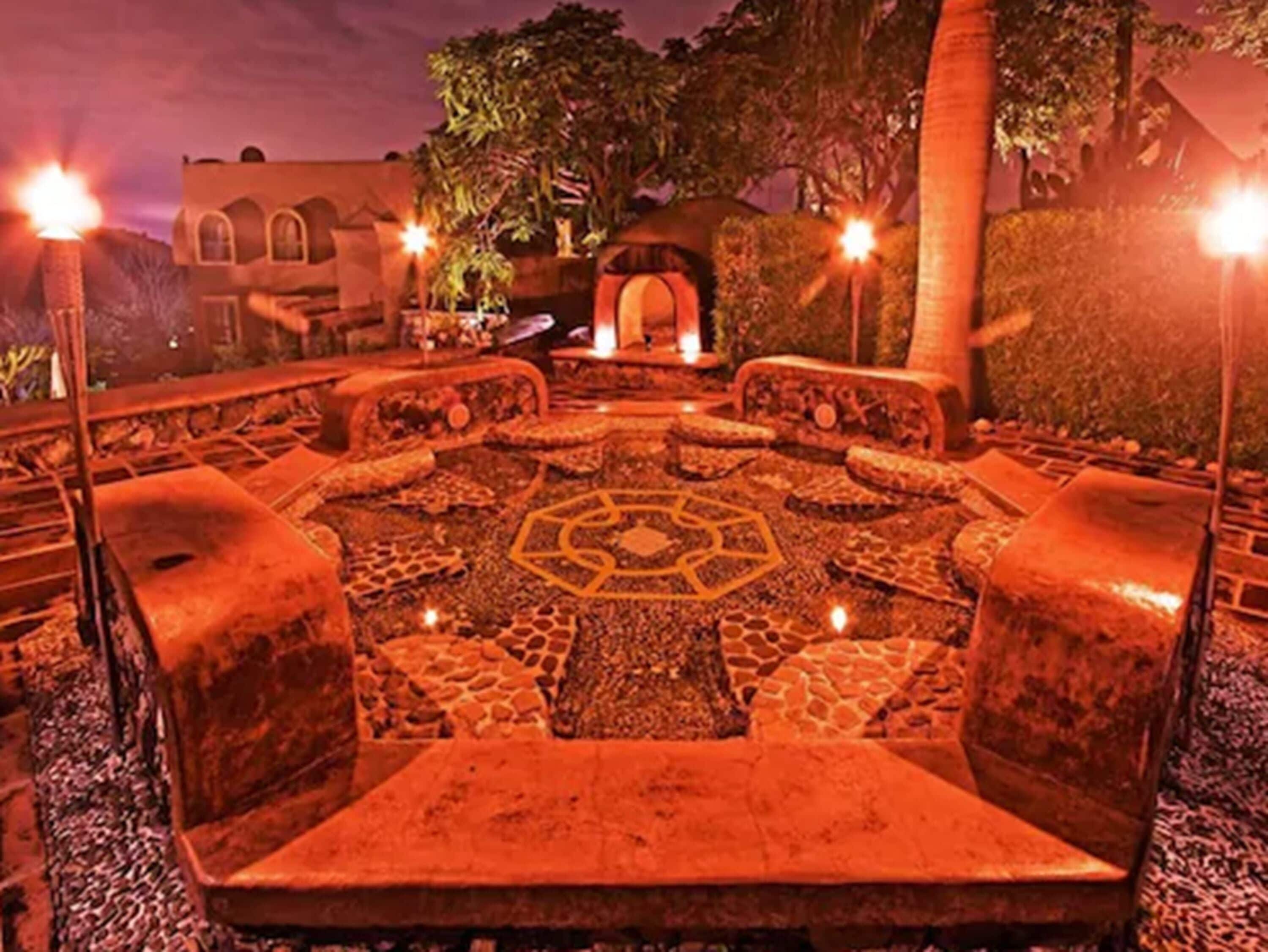 A circular seating area with stone patterns, surrounded by stone benches and a central table.