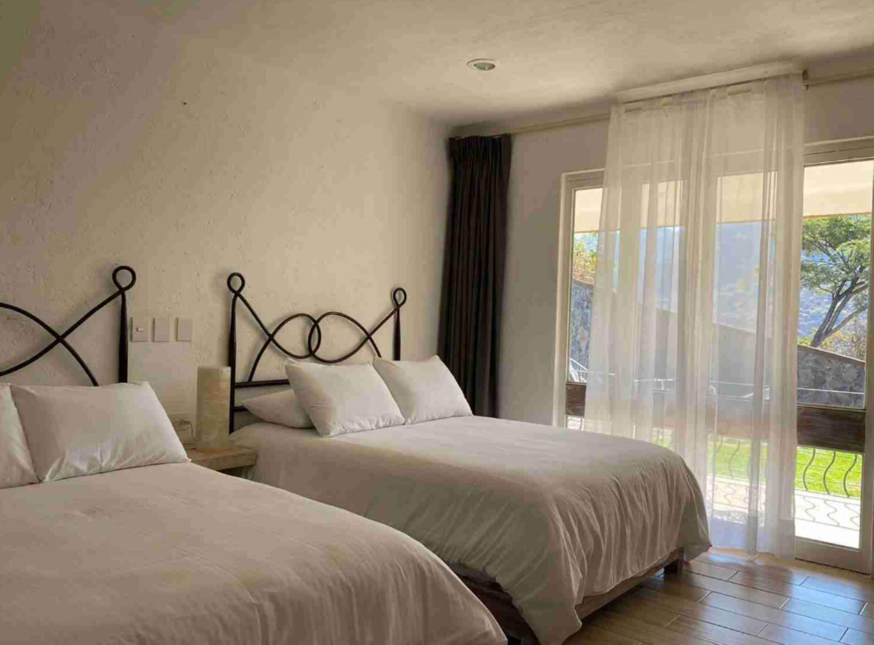 Un dormitorio con dos camas, una ventana con cortinas y vistas al exterior.