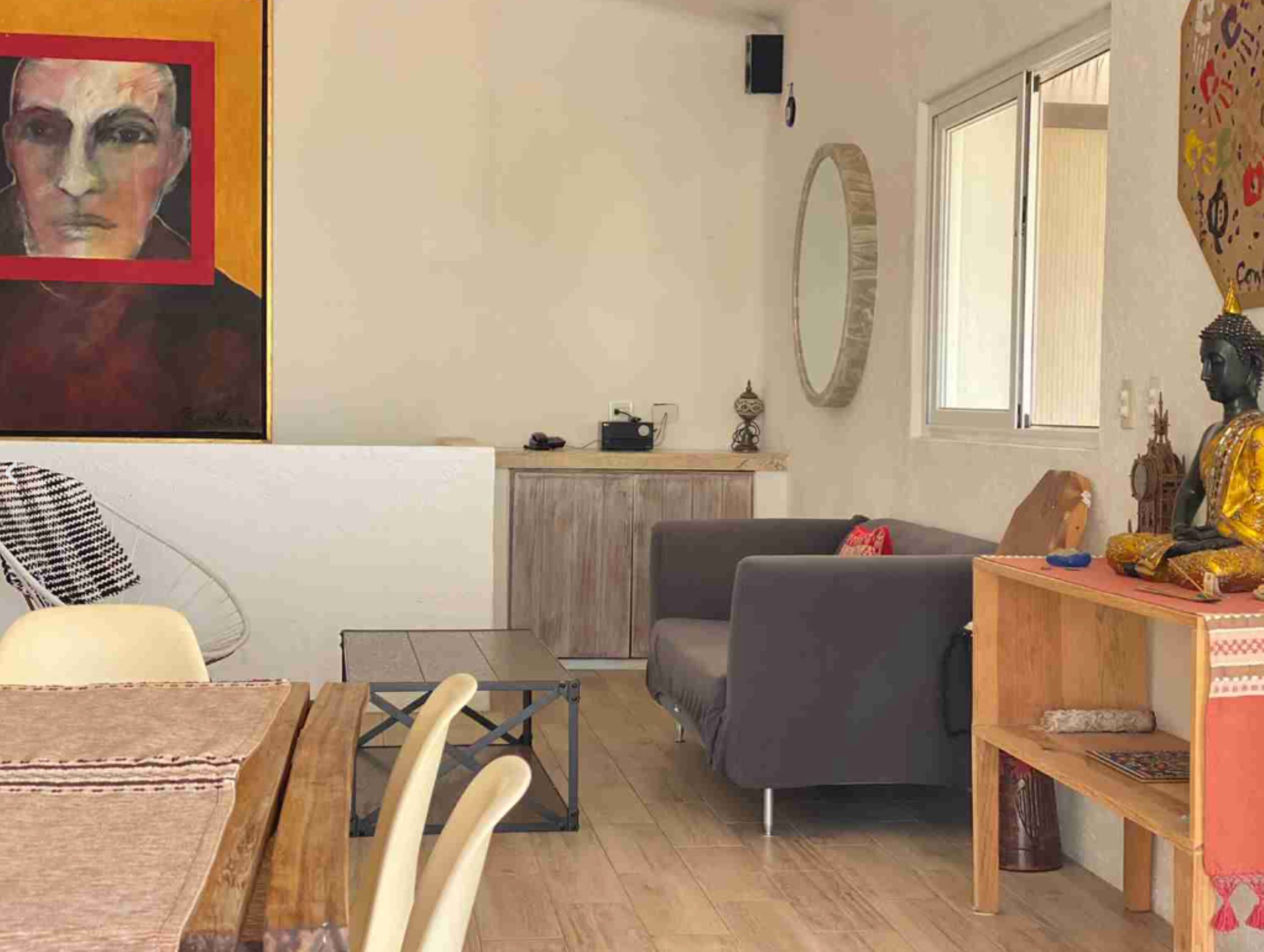 A living room with a sofa, a coffee table, and a Buddha statue.