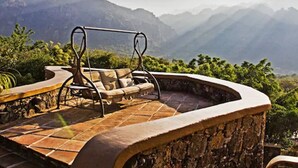 Un patio de piedra con una silla mecedora con vistas a un paisaje montañoso.