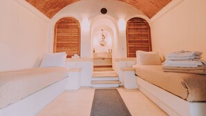 Un dormitorio con dos camas, techo de ladrillo y una escalera central que lleva a un baño.