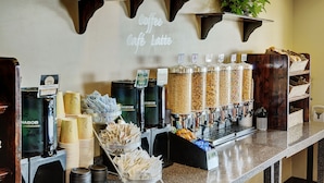 A coffee station with multiple dispensers, paper cups, and a sign reading "Coffee Café Latte". - Lakeview Inns & Suites - Slave Lake (Slave Lake)