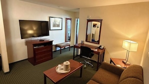 A hotel room with a flat-screen TV, a desk, a chair, a sofa, a dresser, and a mirror. - Lakeview Inns & Suites - Slave Lake (Slave Lake)