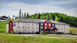 A hotel with a red and beige facade, multiple windows, and a parking lot. - Lakeview Inns & Suites - Slave Lake (Slave Lake)