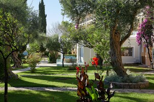 Un jardín con un sendero que conduce a un edificio de fachada blanca y balcón.